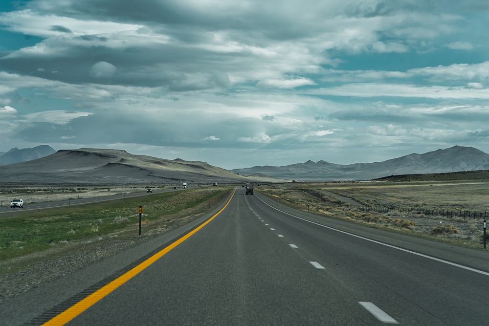 highway toward scenic mountainscape with sparse traffic. Image Credit: AdobeStock_502427825